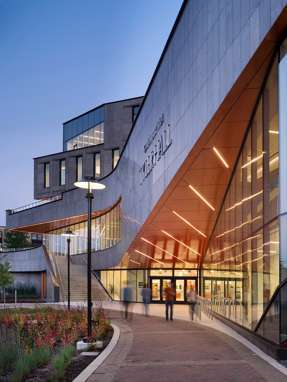 Students and visitors are drawn towards the street-level entrance by the sweeping lines of the facade. An exterior stair stitches the landscaped arrival court with the campus commons above. | nic lehoux photographie architecturale | architectural photography
