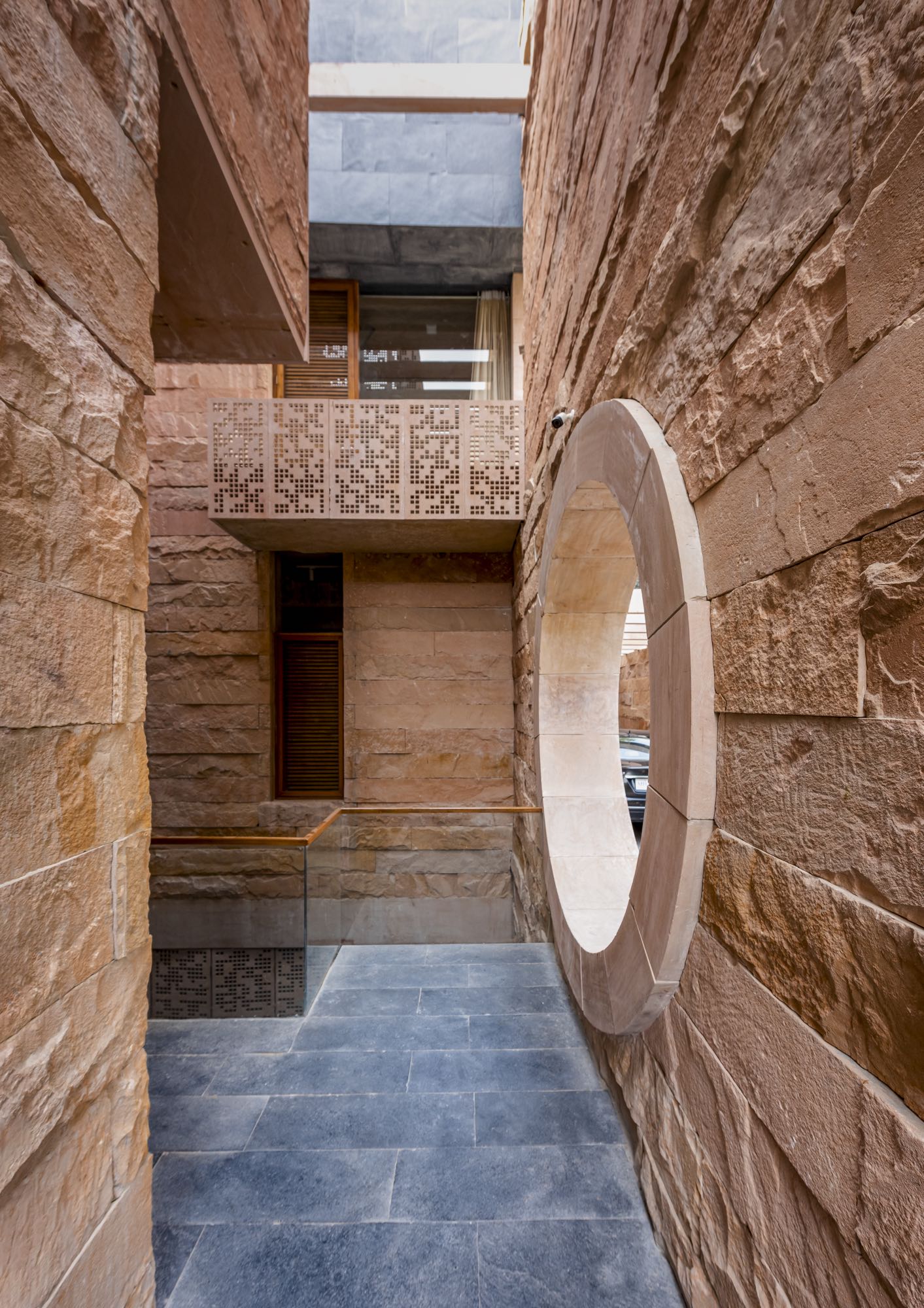 The main entry into the house through a split between monumental stone walls leads to a naturally ventilated courtyard that connects the ground, sunken court, and the sky. Even within a restricted footprin Bharath Ramamrutham