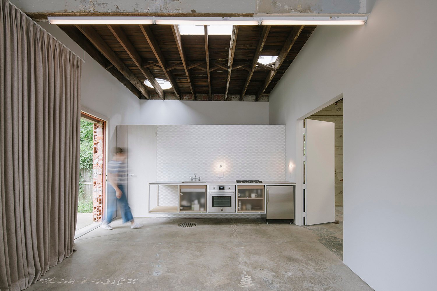 Photograph showing the infrastructure zone for the small space - a wall-hung kitchen area sits directly in front of a bathroom and laundry area. The utilities are condensed into the smallest area possible | Florian Holzherr