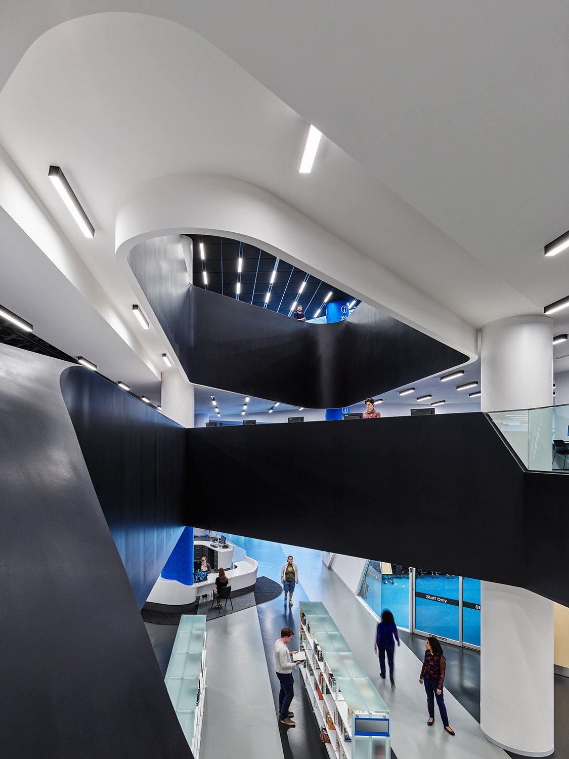 The view from the second floor escalator. The monochrome palette and cut-outs frame views into the library’s varied spaces. | Andrew Latreille, Latreille Architectural Photography