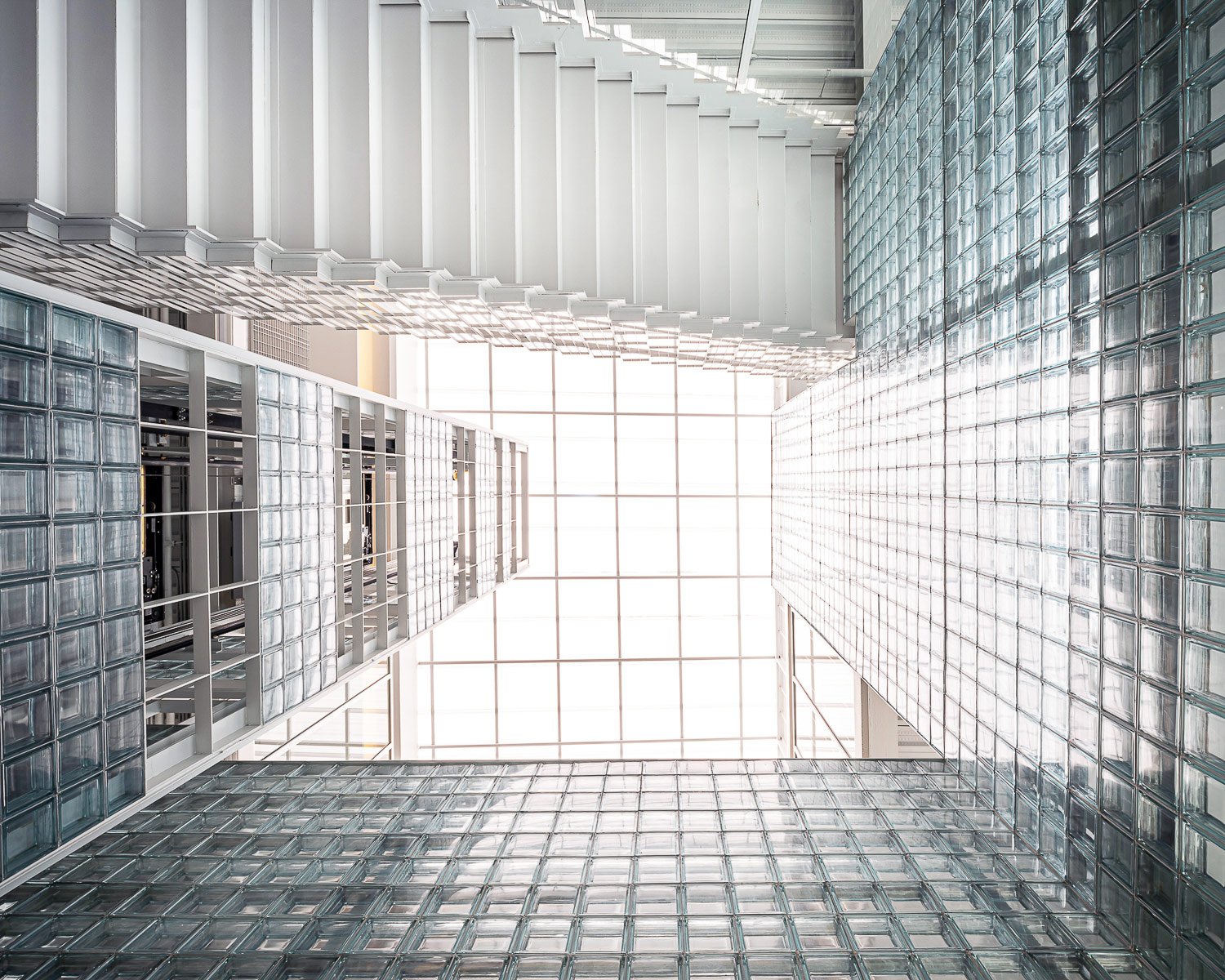 Triple Volume Space : A dramatic grand triple-height space encased in glass blocks, marrying architectural grandeur with functional, light-enhancing elements, enhancing the feeling of openness and integrating various building levels visually. | © Spaceshift Studio