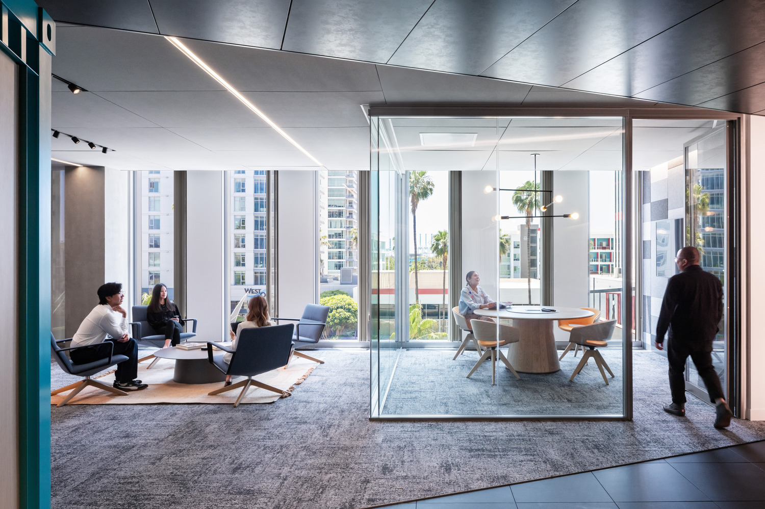 Standing in the kitchenette, tucked under the bold black ribbon, views of the Port of Long Beach can be seen peeking through the full glass partition of the huddle room and adjacent collaborative hospitality zone. | Paul Vu