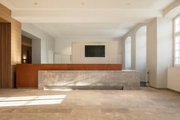 The reception becomes a mediating center between the old and new building – dominated by light natural stone and leather. | HGEsch, Hennef