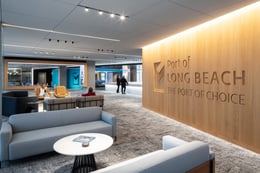 As guests enter the space, they are welcomed into the Hospitality Zone, where soft lounge seating invites relaxation and a stunning wood-wrapped wall showcases the Port of Long Beach brand logo | Paul Vu